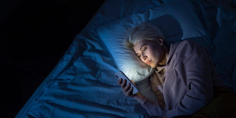 Ilustrasi perempuan asyik bermain ponsel di malam hari/Freepik