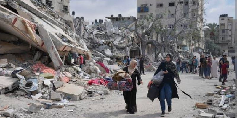 Perempuan Palestina berjalan melintasi reruntuhan bangunan di pusat Jalur Gaza. (AP/Hatem Moussa)